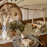 Easter-themed table setting with bunny figurine, decorative plates, and basket.