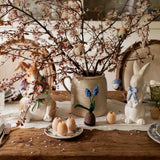 Decorative Easter table setting with branches, eggs, and ceramic bunnies.