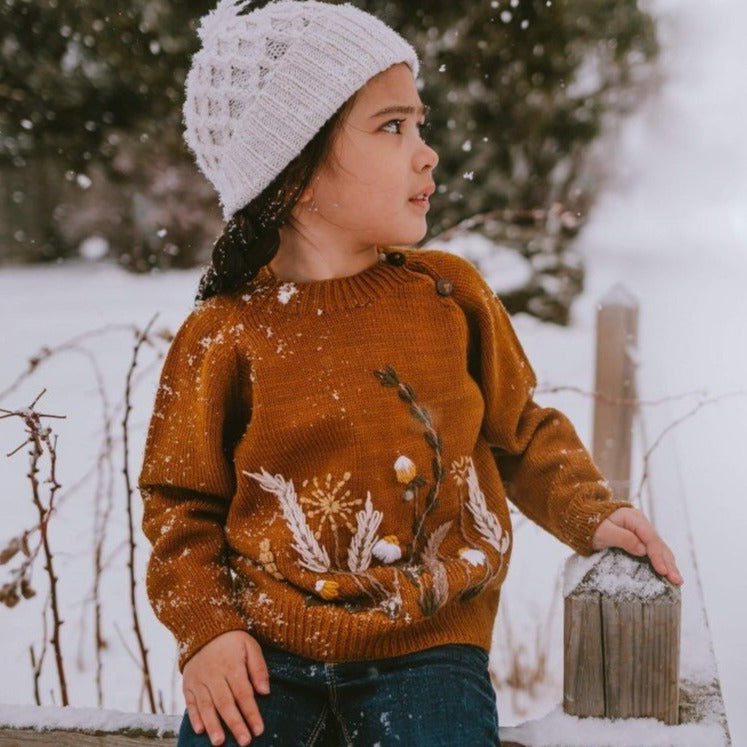 little girl in amber hand knitted and embroidered sweater