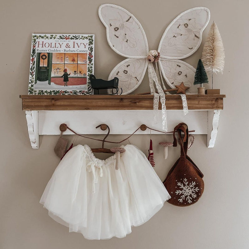 Caramel snowflake bonnet displayed in a festive holiday setting, surrounded by Christmas decorations and other winter apparel.