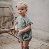 baby girl wearing hand knitted romper with floral embroidery on the front chest  and sleeve part, she looks so adorable on this outfit