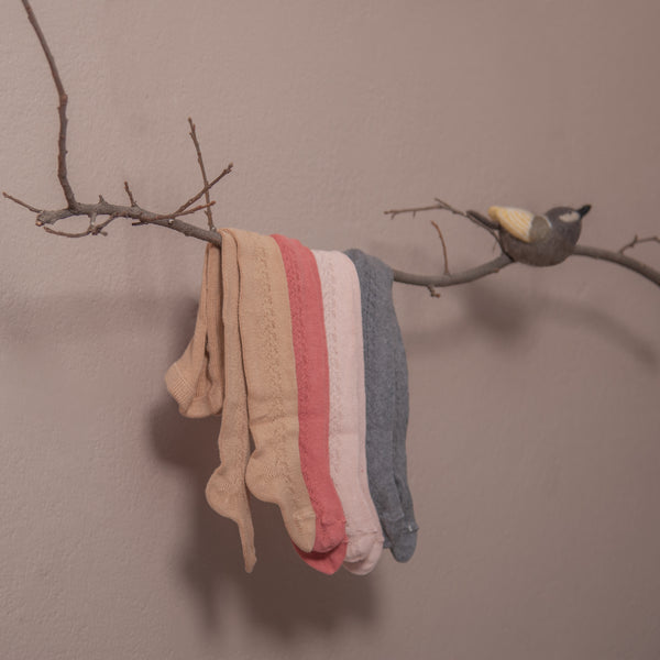 baby tights in hole pattern on side hanging on branch of tree in four different colours : camel,pink, dusty pink and dark grey