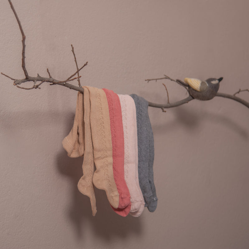 baby tights in hole pattern on side hanging on branch of tree in four different colours : camel,pink, dusty pink and dark grey