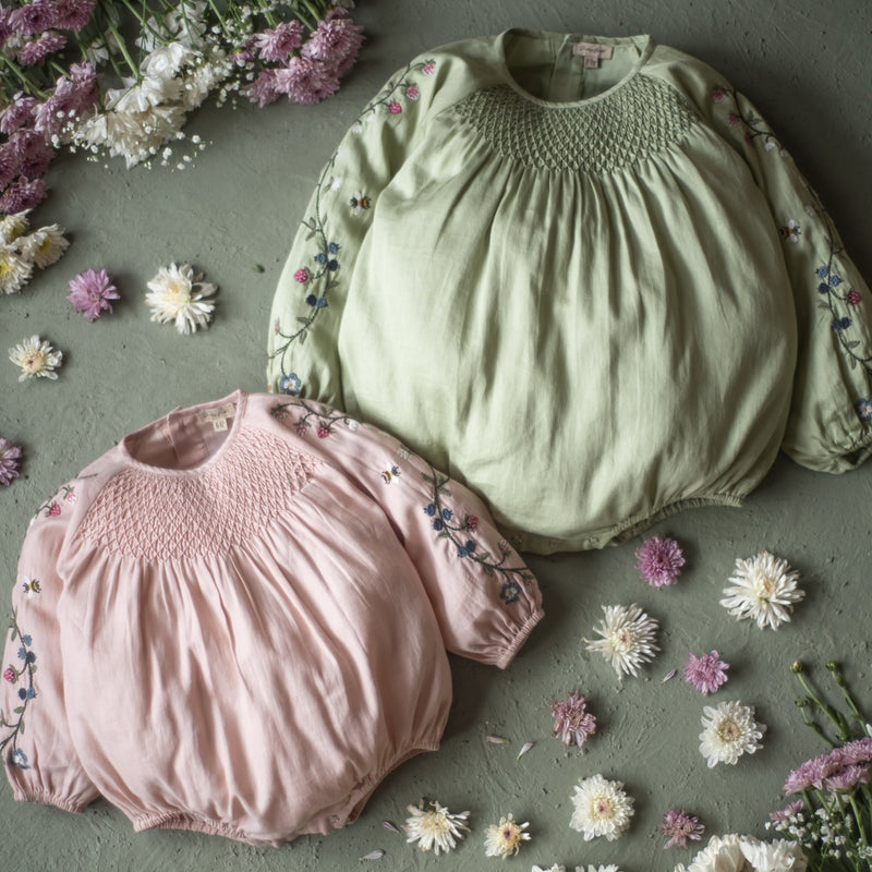 Saoirse Romper in two colors, surrounded by flowers.