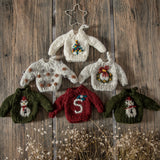 Collection of knitted sweater ornaments with embroidered wreaths displayed on a table