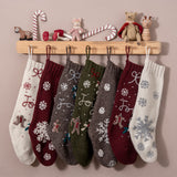 Various Gingerbread Stockings displayed on a wall-mounted hook with a range of festive decorations, highlighting their unique colors and knitted textures in a holiday setting.







