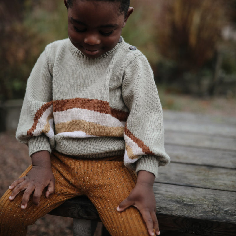 little boy in knitted pistachio sweater and yellow wool leggings