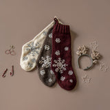 Various Christmas stockings displayed on a surface, surrounded by festive decorations, showcasing different designs and colors.