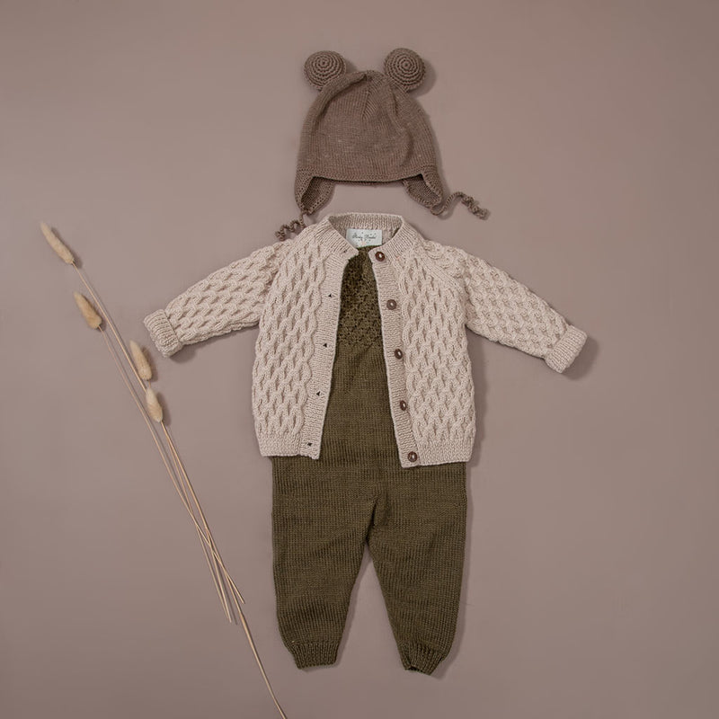 flat lay picture of hand knitted cardigan in waffle style along with hand knitted jumpsuit which has also waffle pattern in front chest part , moss in color and hand knitted bonnet with string ties and ears on it in nutty brown colour