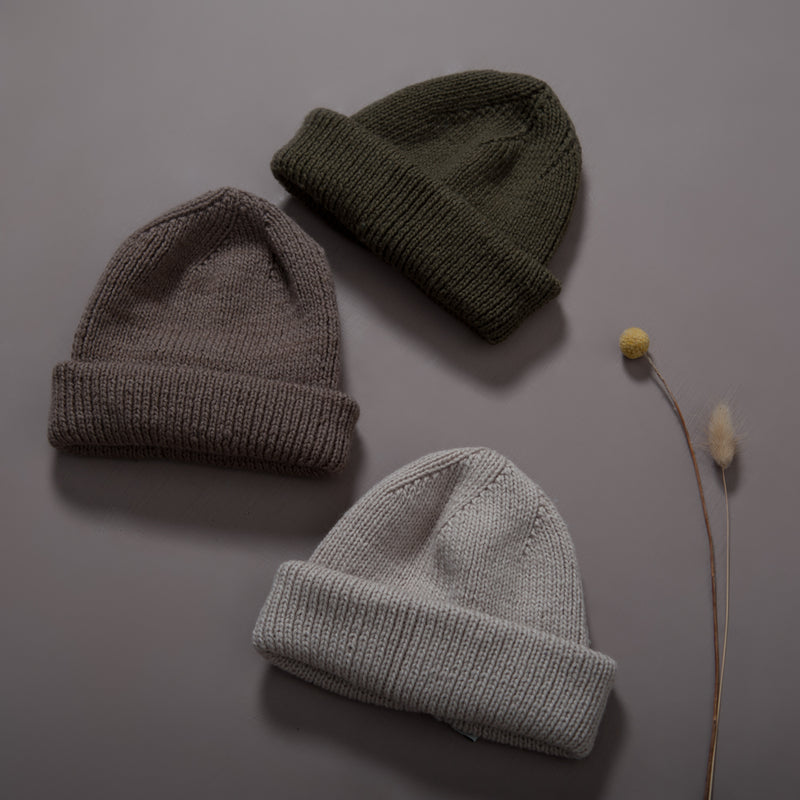Flat lay picture of a slight oversize hat in three different colors: oats,moss and nutty brown that works so well for both mama, boys and girls.The entire hat is knitted in rib in our soft signature merino