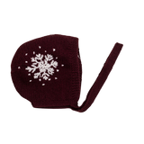 Hand-knitted snowflake bonnet in dark grape color, featuring large embroidered snowflakes on each side and tie bands under the chin.