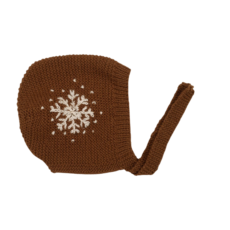 Hand-knitted caramel snowflake bonnet with large embroidered snowflakes on each side and tie bands under the chin, made from soft 100% merino wool.