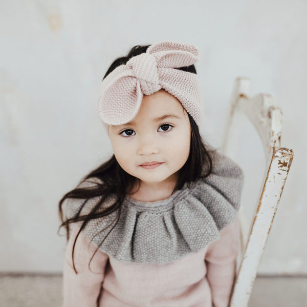 Baby girl wearing hand knitted hairband in dusty pink