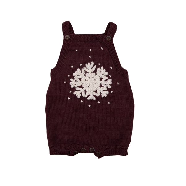 Hand-knitted dark grape romper with large front snowflake embroidery and scattered snowflakes, featuring adjustable button straps and ribbed thigh closures.