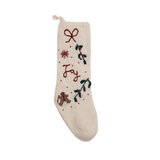 Cream white Gingerbread Stocking with hand-embroidered JOY/snowflake pattern, displayed in a festive setting, showcasing its knitted woolen texture and Christmas charm.