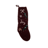 Dark grape Gingerbread Stocking with hand-embroidered JOY/snowflake pattern, displayed in a festive setting, showcasing its knitted woolen texture and Christmas charm.