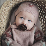 Sweet little baby wearing beautiful hand knitted bonnet with string ties and floral embroidery on it